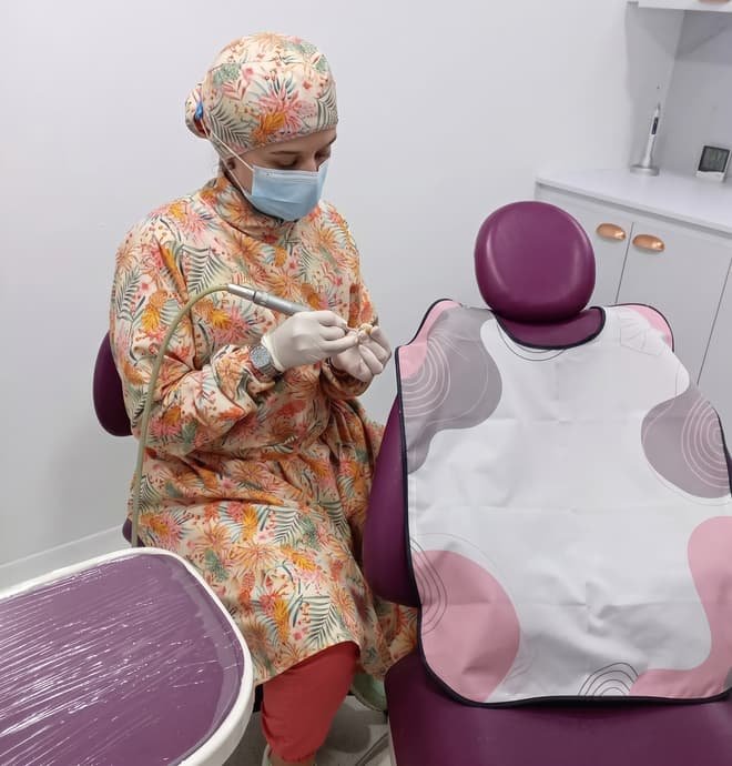 La doctora Katherynne Suárez de pie en su consultorio, con la silla odontológica al fondo