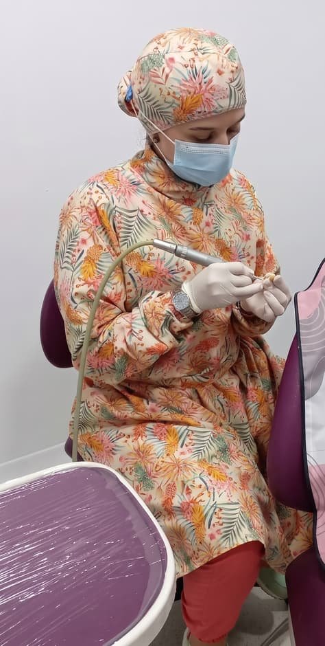 La doctora Katherynne Suárez atendiendo en la silla del consultorio, con gorro, tapabocas y bata estampada