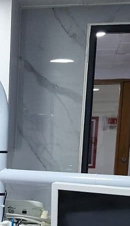 Pared de mármol claro con venas grises y la puerta del consultorio al fondo